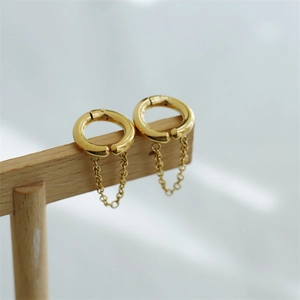 Detailed view of gold tassel ear clips on a T-stand featuring polished chain drop pendants