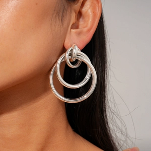 Macro side view of a model wearing minimalist silver tiered hollow circular drop earrings
