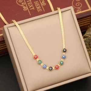 Detailed shot of golden snake chain necklace with colorful evil eye charms in a box