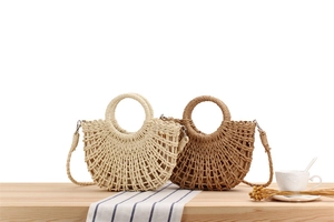Detail of semi-circle woven paper straw bag with hollow texture in beige and tan colors