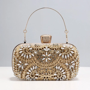 Close-up of golden evening clutch with intricate floral rhinestones and metal handle