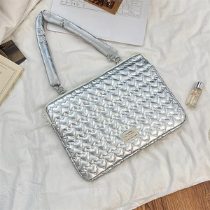Silver metallic quilted tablet bag featuring heart stitching and padded handle detail