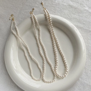 Detailed comparison of three different baroque pearl sizes on a ceramic plate necklace display