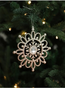 Sparkling glitter snowflake Christmas ornament with center gem on green tree branch