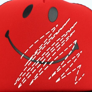 Gros plan d'une casquette rouge avec motif de sourire noir et coutures blanches