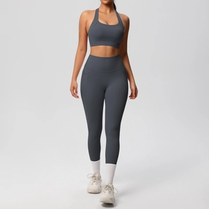 Detail view of high-waist yoga leggings with side pockets and criss-cross sports bra in dark grey