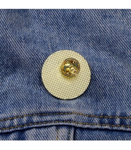 Close-up of golden metal brooch back with pin clasp on blue denim fabric background