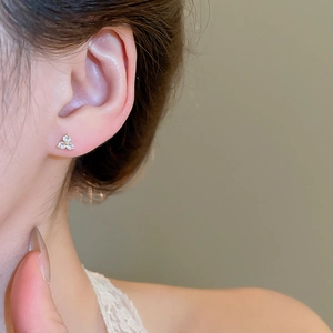 Close-up of elegant gold zircon flower studs worn on a model's ear for a refined look