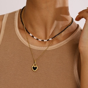 Layered gold heart pendant necklace with black beads and pearls shown on model neck