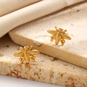 Macro shot of gold-finished stainless steel bee stud earrings with fine engraved texture