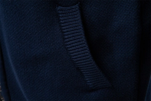 Detailed macro view of dark blue knit fabric showing ribbed pocket edges and texture