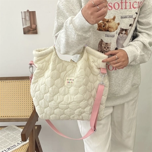 Détail du sac matelassé crème avec écusson coloré et bandoulière rose réglable