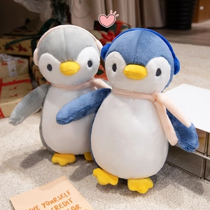 Close-up of cute plush penguin dolls with earmuffs and scarves in a gift setting