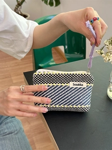 Handwoven striped cosmetic bag with contrast colors and purple wrist strap lanyard