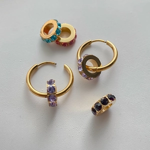 Nahaufnahme von goldenen Edelstahl-Creolen mit bunten austauschbaren Zirkonia-Ringen