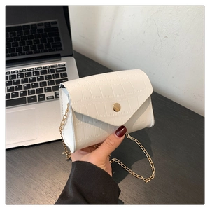 Detail of white crocodile pattern small square bag with elegant gold chain and snap closure