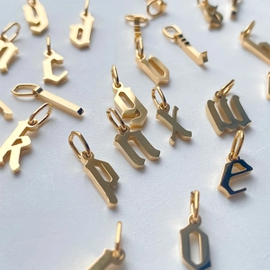 Macro detail of gothic style gold-plated initial pendants with high-polish finish