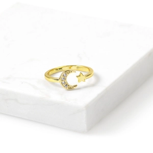 Golden moon and star open ring with sparkling cubic zirconia on a white marble base