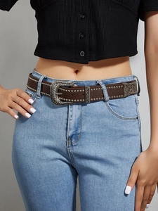 Close-up of vintage brown leather punk belt with metal studs and engraved silver buckle