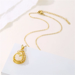 Detailed close-up of golden pear pendant with white stone and intricate vine pattern