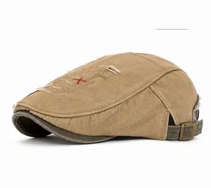 Détail d'un béret kaki avec effet usé, broderie rouge et boucle métallique réglable