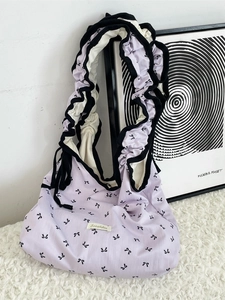 Lavender purple tote bag with ruffle straps and black bow patterns in a clean room setting