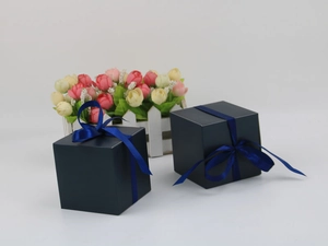 Navy blue square paper gift boxes with matching satin ribbons on white background