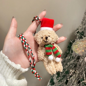 Close-up of a khaki flocked Christmas bear pendant with a red hat and festive striped scarf