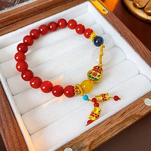 Macro detail of red agate beads bracelet with gold gourd pendant in a wood jewelry box