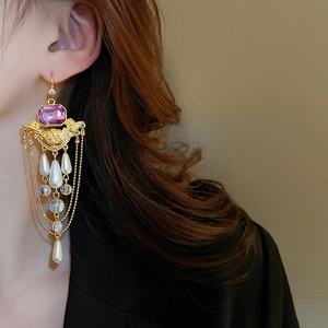 Vue détaillée des boucles d'oreilles dorées vintage avec pierre mauve et perles