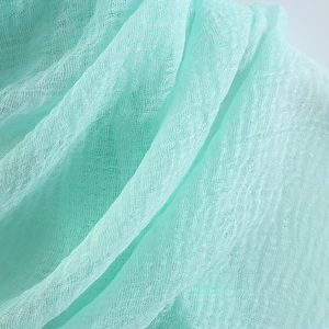 Macro detail of pleated light green cotton linen fabric with soft texture and weave
