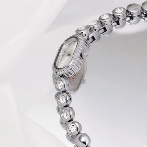 Macro shot of silver quartz watch with oval bezel and beaded cubic zirconia chain