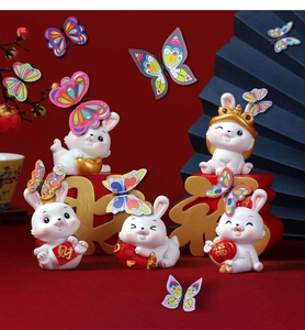 Macro detail of white resin rabbit figurines with butterfly and festive New Year charms