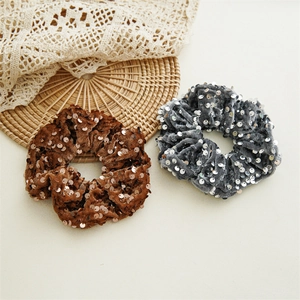 Detailed view of sequined velvet scrunchies in coffee and grey showing rich material texture