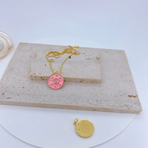 Detail of pink enamel sakura pendant with gold star motifs on a textured stone base