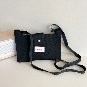 Close-up of black knitted crossbody bag with diamond texture and magnetic buckle