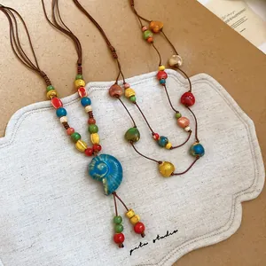 Dettaglio del ciondolo a conchiglia in ceramica e collana bohémien con perline colorate