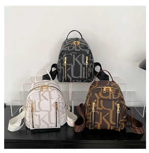Detailed view of three monogrammed leather backpacks with gold hardware and zippers