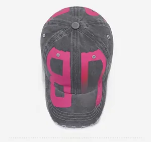 Close-up of distressed gray washed denim baseball cap with pink BB logo and frayed edges
