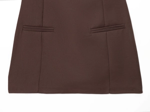 Detailed view of symmetric flat pockets and stitching on a dark brown short dress