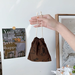 Brown corduroy storage bag with bear print and white drawstring held in hand