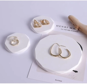 Artistic layout of gold earrings and rings on geometric stands with dry wood decor