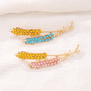 Detailed macro view of gold wheat brooches with blue and pink crystal rhinestones