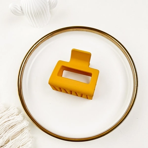 Detail of yellow matte square hair claw clip on white decorative plate
