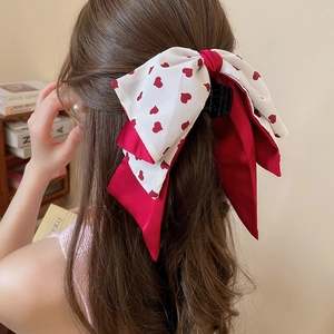 Détail d'une pince à cheveux avec nœud rouge et blanc à imprimé cœur en satin