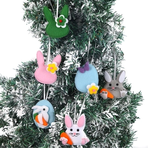 Gros plan de décorations de Pâques en feutre lapin et œuf sur une branche enneigée
