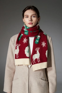 Detailed knit texture of red Christmas scarf featuring white reindeer and snowflake patterns