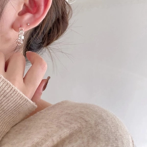 Elegant 925 sterling silver twist hoop earrings worn by a model in a minimal setting