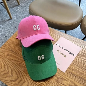 Pink and green cotton baseball caps with crystal CC embroidery on wooden surface