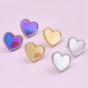 Macro detail of heart-shaped stainless steel earrings in purple, gold, and silver
